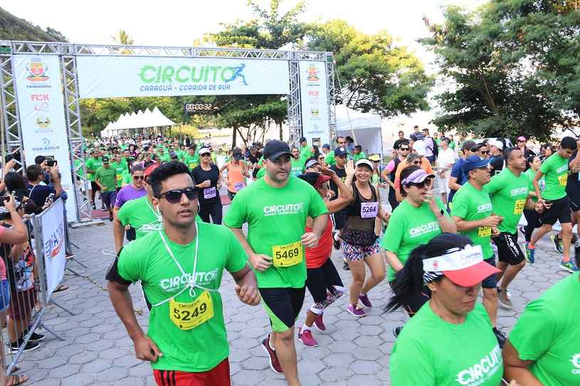 Foto 1_Corredores saem juntos da linha de largada com camisa verde da corrida