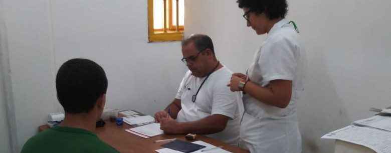 Médico e enfermeira em sala realizam consulta a um jovem rapaz