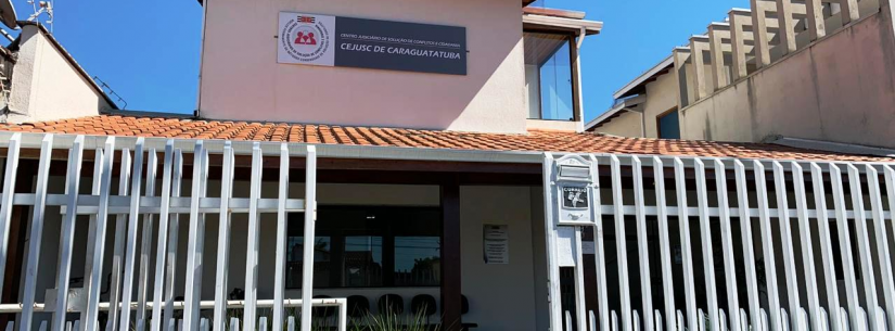 Fachada do Cejusc, sobrado da cor rosê, com portão branco de alumínio e gramado na varanda. Em cima, placa escrito Cejusc de branco e fundo azul