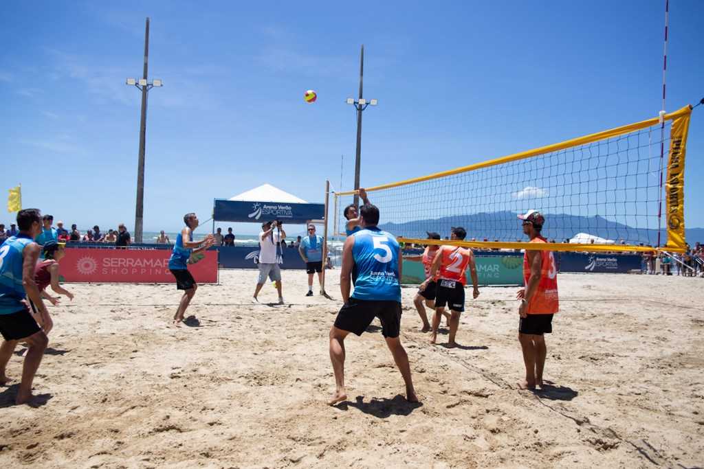 Festa na praia. atividades de férias de verão. jovens jogando vôlei na  costa arenosa e ouvindo música. esporte tropical, verão. jogo de bola.